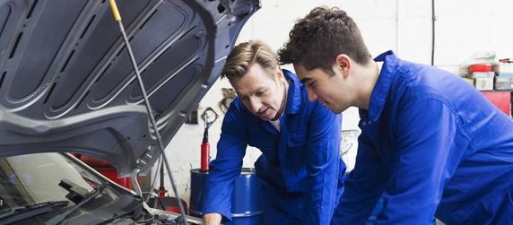 Mechaniker die in den Motorraum eines Autos schauen