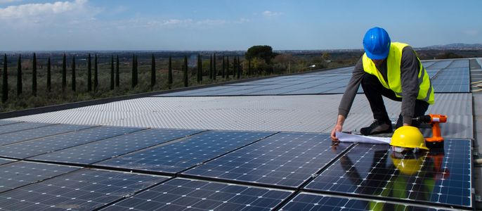 Ein Techniker schaut sich auf einer Solaranlage Pläne an.