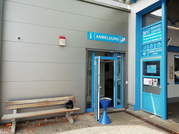 Ein Gebäude mit einer blauen Tür mit der Aufschrift "ANMELDUNG" und einem Schild darüber mit der Aufschrift "SERVICE CENTER", auf dem verschiedene Dienstleistungen aufgeführt sind.