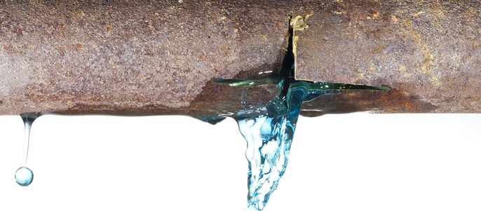 Ein verrostetes Metallrohr, aus dem eine blaue Flüssigkeit tropft.