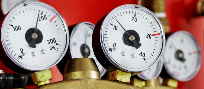 Mehrere Manometer mit unterschiedlichen Messwerten auf rotem Hintergrund.