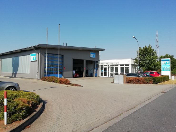 Ein modernes Gebäude mit blau-weißer Fassade, einem Schild mit der Aufschrift "Motor Service" und ein paar geparkten Autos.