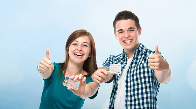 Zwei Personen, ein Mann und eine Frau, zeigen beide mit ihren Händen den Daumen nach oben. Sie halten ihre Ausweise hoch.
