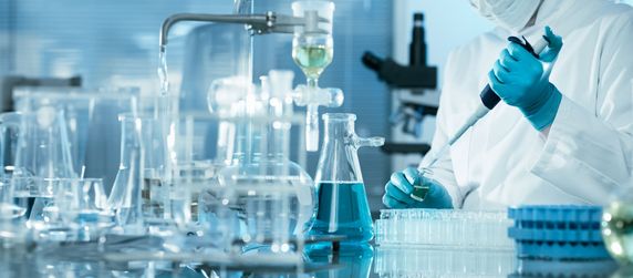 Eine Laborsituation, in der ein Wissenschaftler mit verschiedenen Glasgeräten, einschließlich Kolben und Pipetten, arbeitet, um ein Experiment durchzuführen.