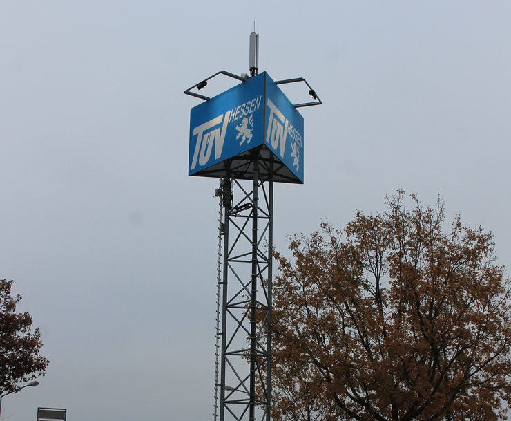 Eine hoheWerbetafel mit einem blauen Schild mit der Aufschrift "TUEV HESSEN".