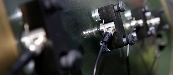 Eine Reihe von schwarzen und silbernen Steckern, die auf einer grünen Fläche montiert sind und an denen Kabel befestigt sind.