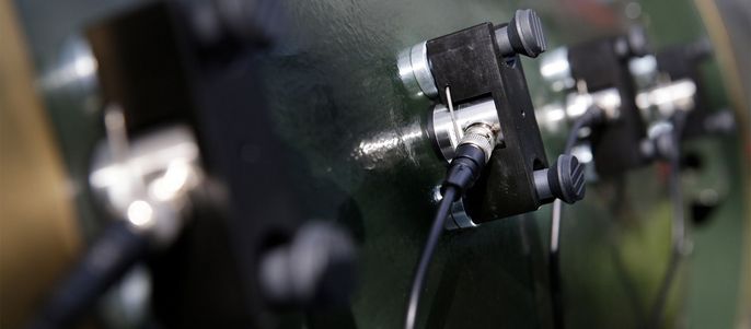 Eine Reihe von schwarzen und silbernen Steckern, die auf einer grünen Fläche montiert sind und an denen Kabel befestigt sind.