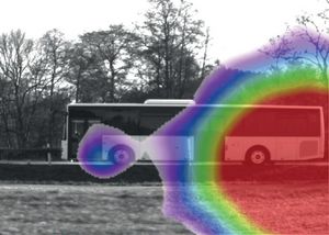 Ein Bus, der auf einer Straße fährt. Durch eine Akustische Kamera wird auf dem Bus eine Rote Farbtönung in Korrelation mit dessen Lautstärke signalisiert