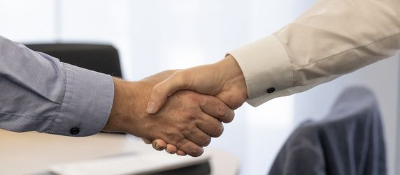 Zwei Personen schütteln sich in einem beruflichen Umfeld die Hände.