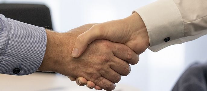 Zwei Personen schütteln sich in einem beruflichen Umfeld die Hände.