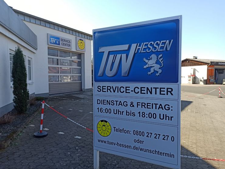 Ein Schild für "TUEV HESSEN" mit Angaben zum Service-Center, einschließlich der Öffnungszeiten.