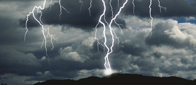 Ein Gewitter mit Blitzeinschlag über einem Wald.