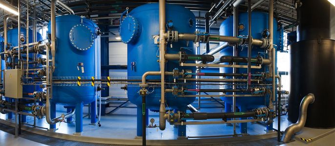 Eine große Industrieanlage mit blauen zylindrischen Tanks, die durch Metallrohre verbunden sind.