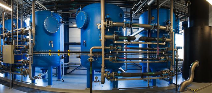 Eine große Industrieanlage mit blauen zylindrischen Tanks, die durch Metallrohre verbunden sind.