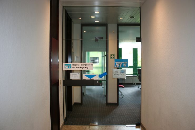Ein Eingang zu einem Raum mit der Aufschrift "Bitte klingeln!!!", mit einem Schild an der Tür, auf dem "Begutachtungsstelle für Fahreignung" steht, und einem weiteren Schild mit der Aufschrift "TUEV Hessen".