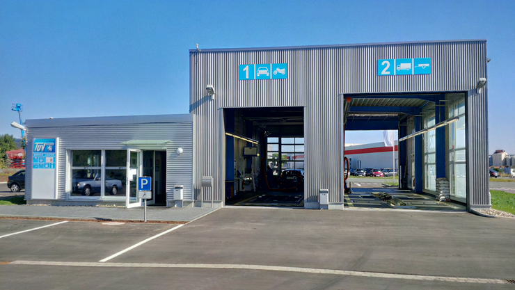 Eine Autowerkstatt mit zwei Fahrspuren, eine für Autos und eine für Busse, mit einem Schild für "TUEV Hessen" auf der linken Seite.
