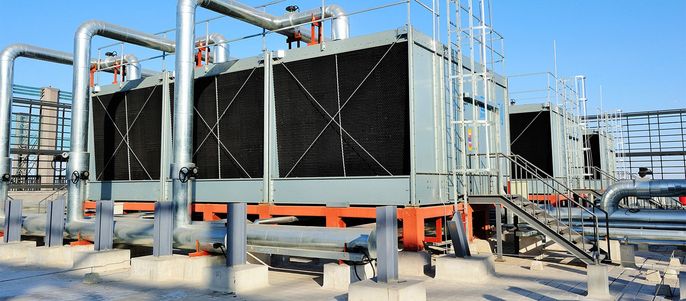 Ein großes industrielles Kühlsystem mit mehreren Komponenten, darunter Rohre, eine Metallstruktur und eine Reihe von schwarzen rechteckigen Platten.