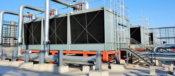 Ein großes industrielles Kühlsystem mit mehreren Komponenten, darunter Rohre, eine Metallstruktur und eine Reihe von schwarzen rechteckigen Platten.