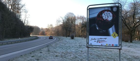Eine Straße mit einem Auto und ein Schild, auf dem ein blutverschmierter Schaltkolben mit dem Wort Egoist, zu sehen ist.