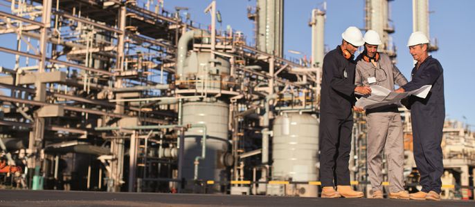 Bauarbeiter vor einer Industriestruktur.
