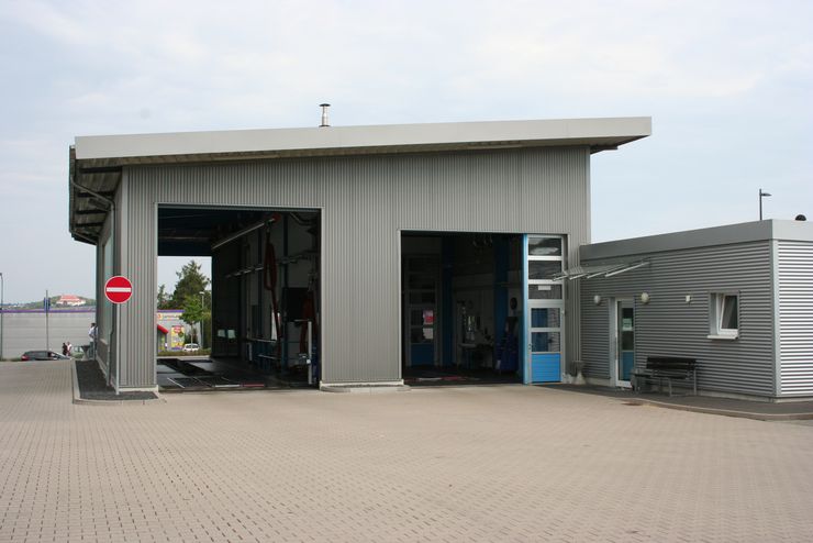 Ein modernes Gebäude mit einem grauen Äußeren, zwei großen Türen und einem Schild von TUEV Hessen.