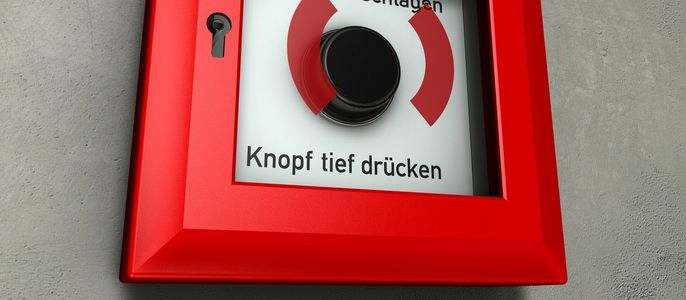 Ein Brandmeldeschalter an einer Zementwand.