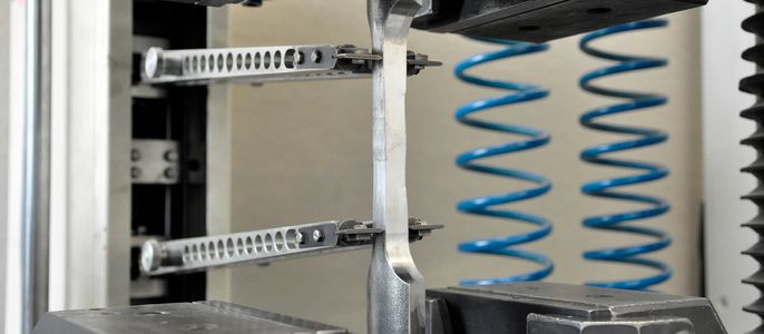 Eine mechanische Vorrichtung mit Metallteilen, einschließlich zwei Federn und Klammern, die an einer Wand befestigt ist.