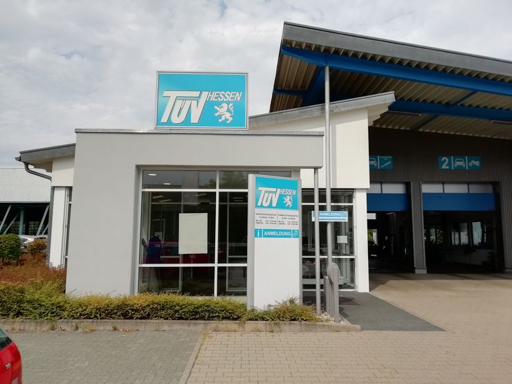 Ein modernes Autowerkstattzentrum mit dem Namen 'TUEV HESSEN' mit einem Schild in Blau und Weiß. Das Zentrum hat ein sauberes und organisiertes Erscheinungsbild.