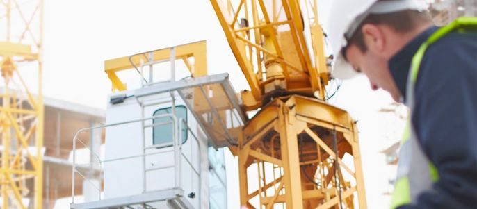 Abmessende Bauarbeiter vor einem Kran auf einer Baustelle.