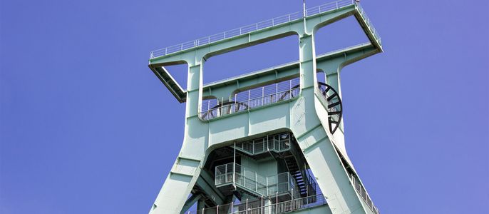 Ein hohes, grünes Bauwerk mit metallischem Rahmen, mit einer Plattform an der Spitze und einer Reihe von Treppen, die nach unten führen.