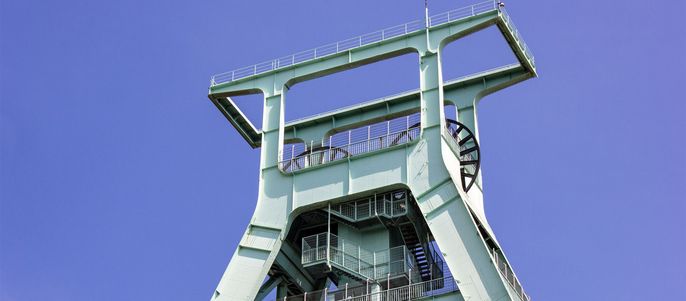 Ein hohes, grünes Bauwerk mit metallischem Rahmen, mit einer Plattform an der Spitze und einer Reihe von Treppen, die nach unten führen.