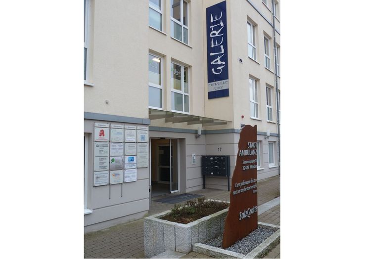 Die Außenseite eines Gebäudes mit dem Schild "GALERIE" und einem weiteren Schild für "STADT AMBULANZ". Außerdem gibt es verschiedene andere Schilder und eine Tür, die ins Innere führt.