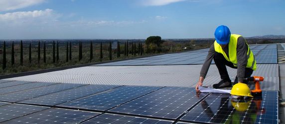 Ein Techniker schaut sich auf einer Solaranlage Pläne an