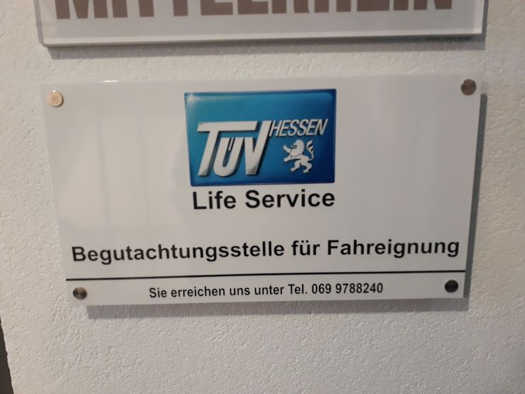 Ein Schild für "TUEV HESSEN Life Service" mit den Kontaktangaben "Sie erreichen uns unter Tel. 069 9788240".