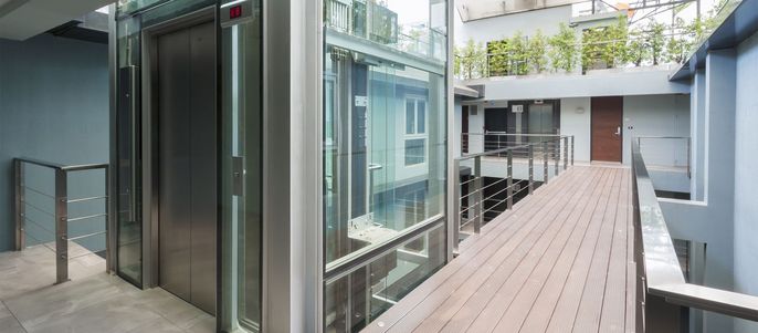 Ein Gläserner Aufzug in einem Gebäude bei Tag.