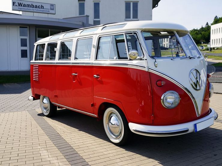 Ein alter rot-weißer VW-Bus parkt vor einem Gebäude mit der Beschriftung "F. Wambach".