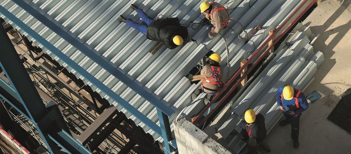 Arbeiter auf einer Baustelle, die an einer Metallkonstruktion arbeiten.