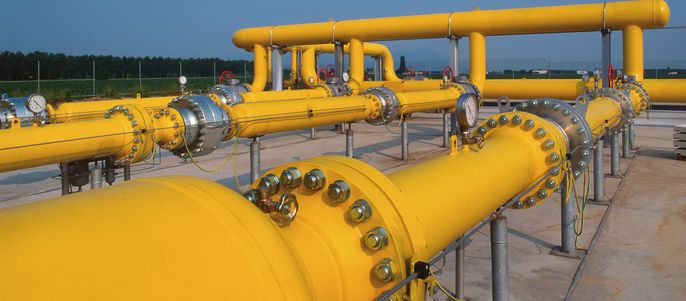 Eine Reihe von gelben Rohren, die mit verschiedenen Ventilen und Armaturen verbunden sind, vor einem klaren blauen Himmel.