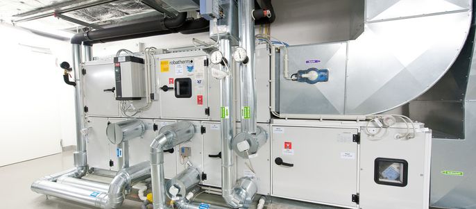 Ein komplexes mechanisches System, das hauptsächlich aus Rohren und Ventilen besteht und sich in einem Raum mit weißen Wänden und einem Metallboden befindet.