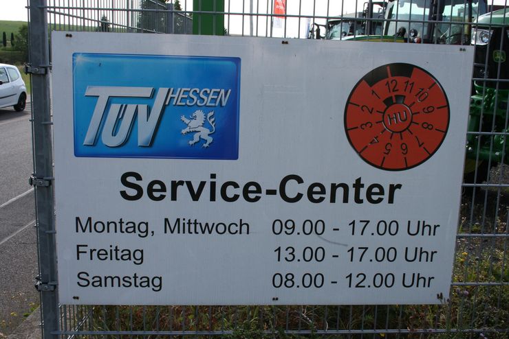 Ein Schild für ein "Service-Center" von "TUEV HESSEN" mit Betriebszeiten von Montag bis Samstag.