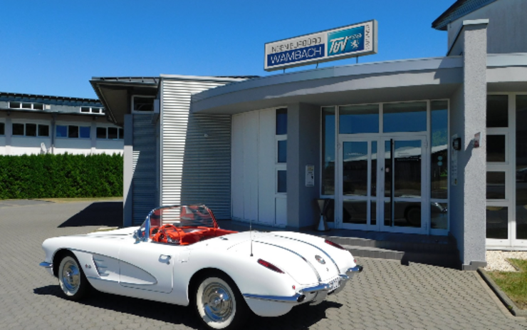Ein weißer Oldtimer parkt vor dem TÜV Hessen Service Center in Wambach.