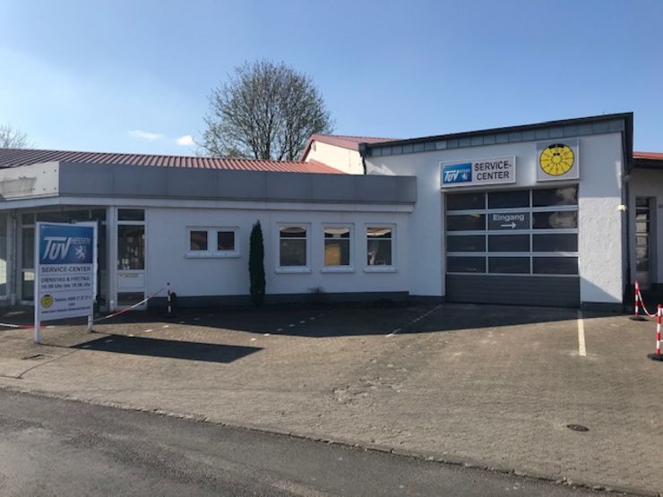 Ein Gebäude mit einem Schild mit der Aufschrift "TUEV Service Center" und einem weiteren Schild mit der Aufschrift "TUEV Service Center". Auf der linken Seite befindet sich auch ein Schild mit der Aufschrift "TUEV Service Center".