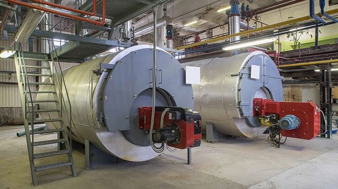 Zwei große zylindrische Kessel in einer industriellen Umgebung, ausgestattet mit roten und grauen Maschinen.