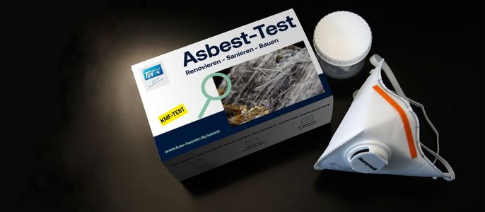 Eine Schachtel mit der Aufschrift "Asbest-Test", in der sich ein Testkit befindet, zusammen mit einer weißen Maske.