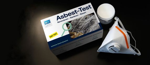 Eine Schachtel mit der Aufschrift "Asbest-Test", in der sich ein Testkit befindet, zusammen mit einer weißen Maske.