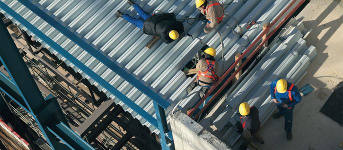 Arbeiter auf einer Baustelle, die Bleche an einem Gebäude anbringen.