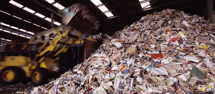 Ein Müllhaufen, auf dem mit einem Bagger, mehr Material aufgeschüttet wird.