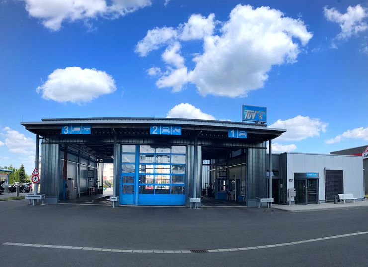 Eine moderne Autowaschanlage mit blauer Beschilderung, einer großen blauen Tür und ein paar Bänken im Freien.